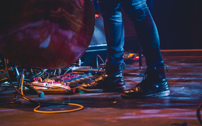 Person in Doc Marten boots is standing on stage playing an electric double bass